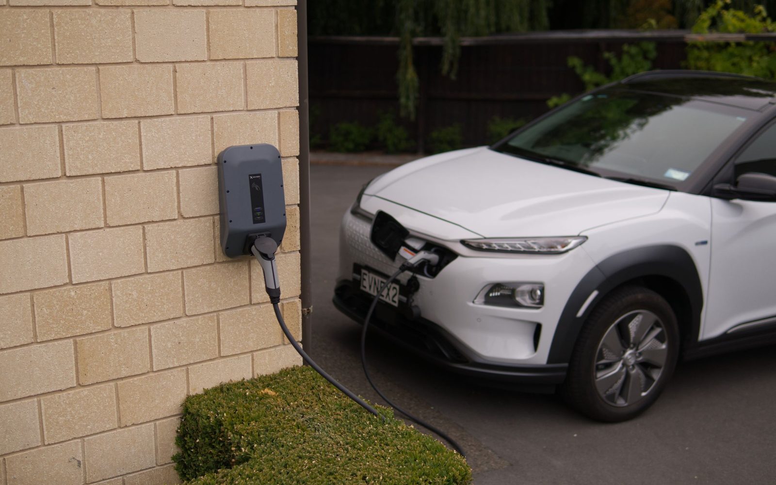 Wallbox an der Hauswand, E-Auto lädt in der Einfahrt
